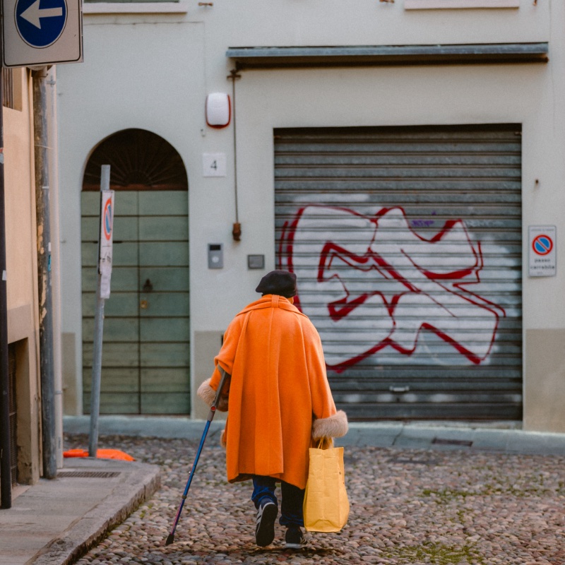 Parma, Italy - December 10, 2023: Elderly lady walking with her back turned in the historic city center of Parma