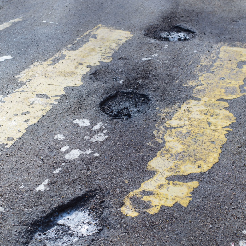 Pits on the road, destroyed asphalt, erased markings of a pedestrian crossing